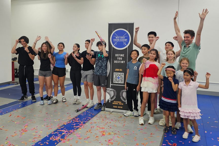 Children and teenagers from West Coast Fencing Academy celebrate in front of the club banner