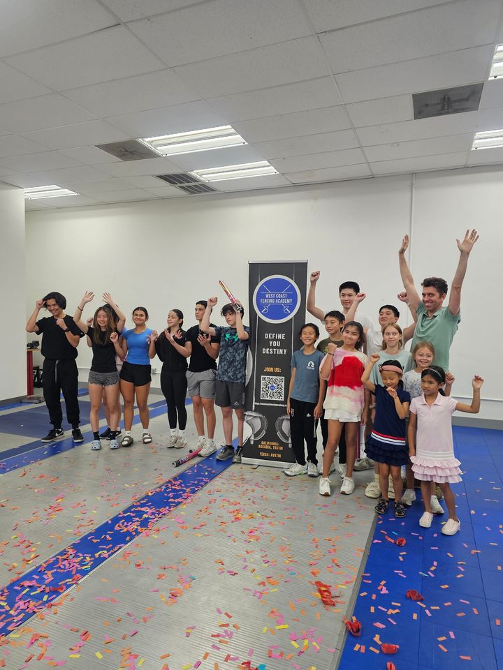 Children and teenagers cheer among confetti around the West Coast Fencing Academy banner